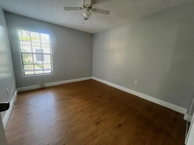 an empty room with windows and fan