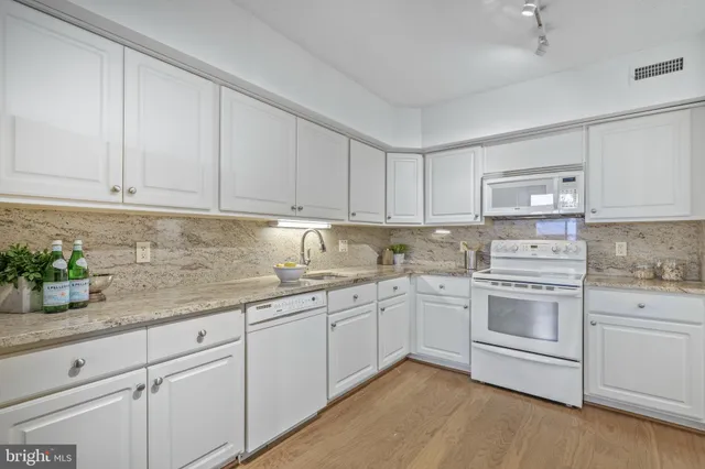 a kitchen with granite countertop white cabinets and white appliances