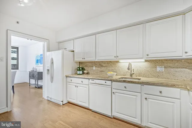a kitchen with granite countertop white cabinets and refrigerator