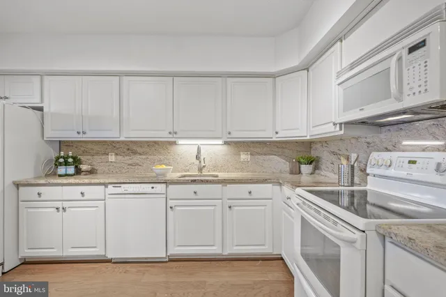 a kitchen with granite countertop white cabinets and white appliances