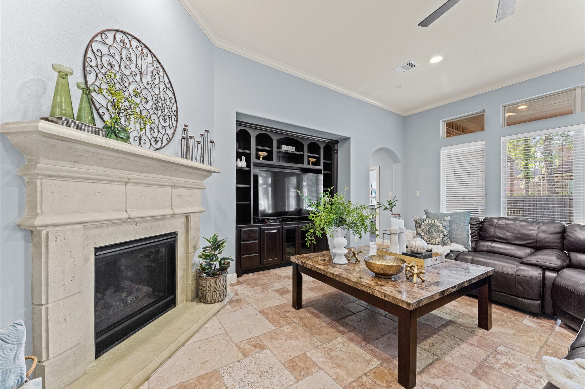 70 Valera Ridge Drive Spring, TX 77389 - Photo 13 of 37 This inviting living room features a cozy fireplace, elegant built-in shelving, and a spacious layout with natural light streaming through large windows. The room's neutral tones and stylish decor create a warm and welcoming atmosphere.