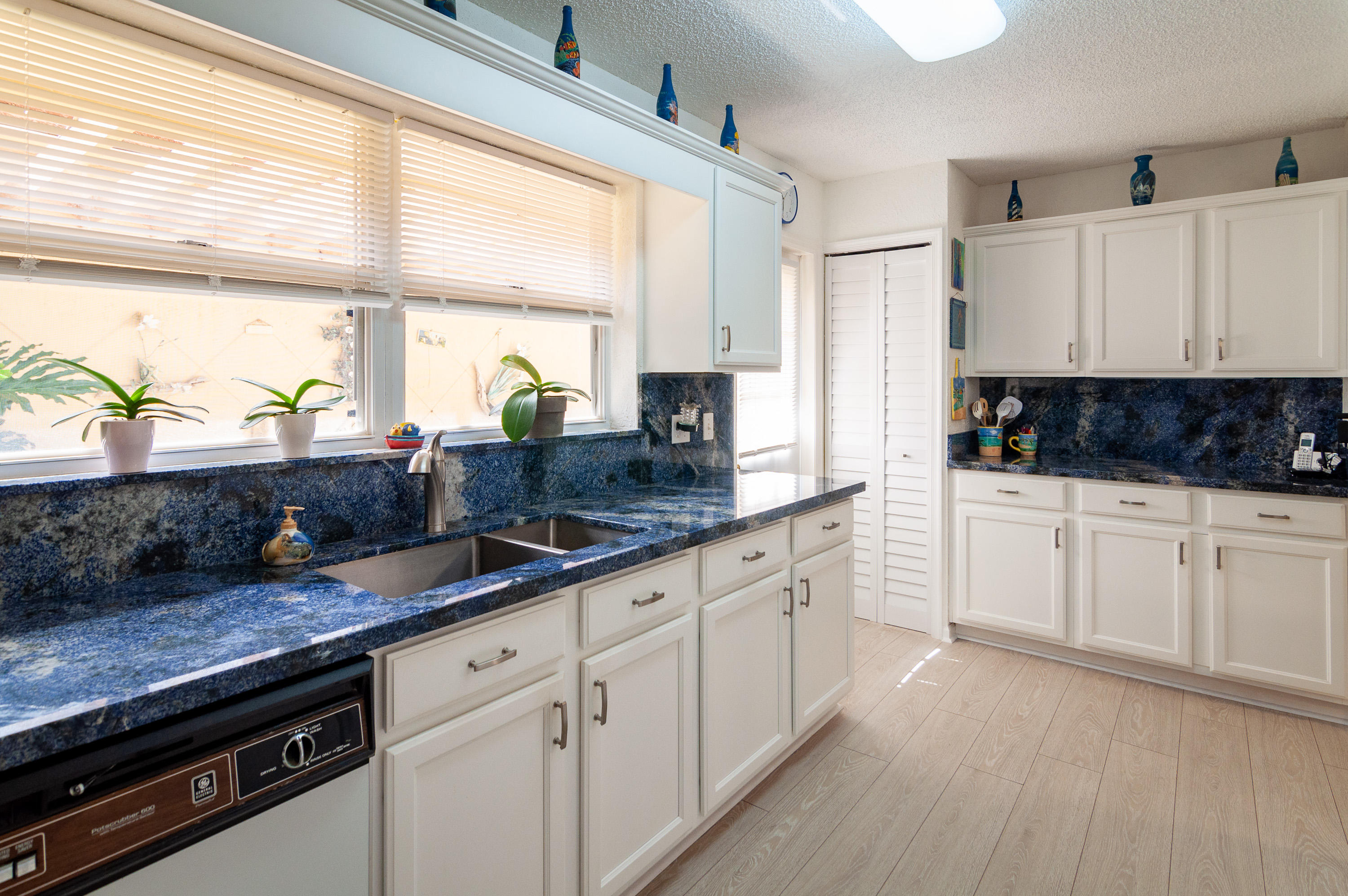 4161 U.S. Highway 1, Unit E2 Jupiter, FL 33477 - Photo 11 of 37 a kitchen with granite countertop white cabinets and white appliances with wooden floor