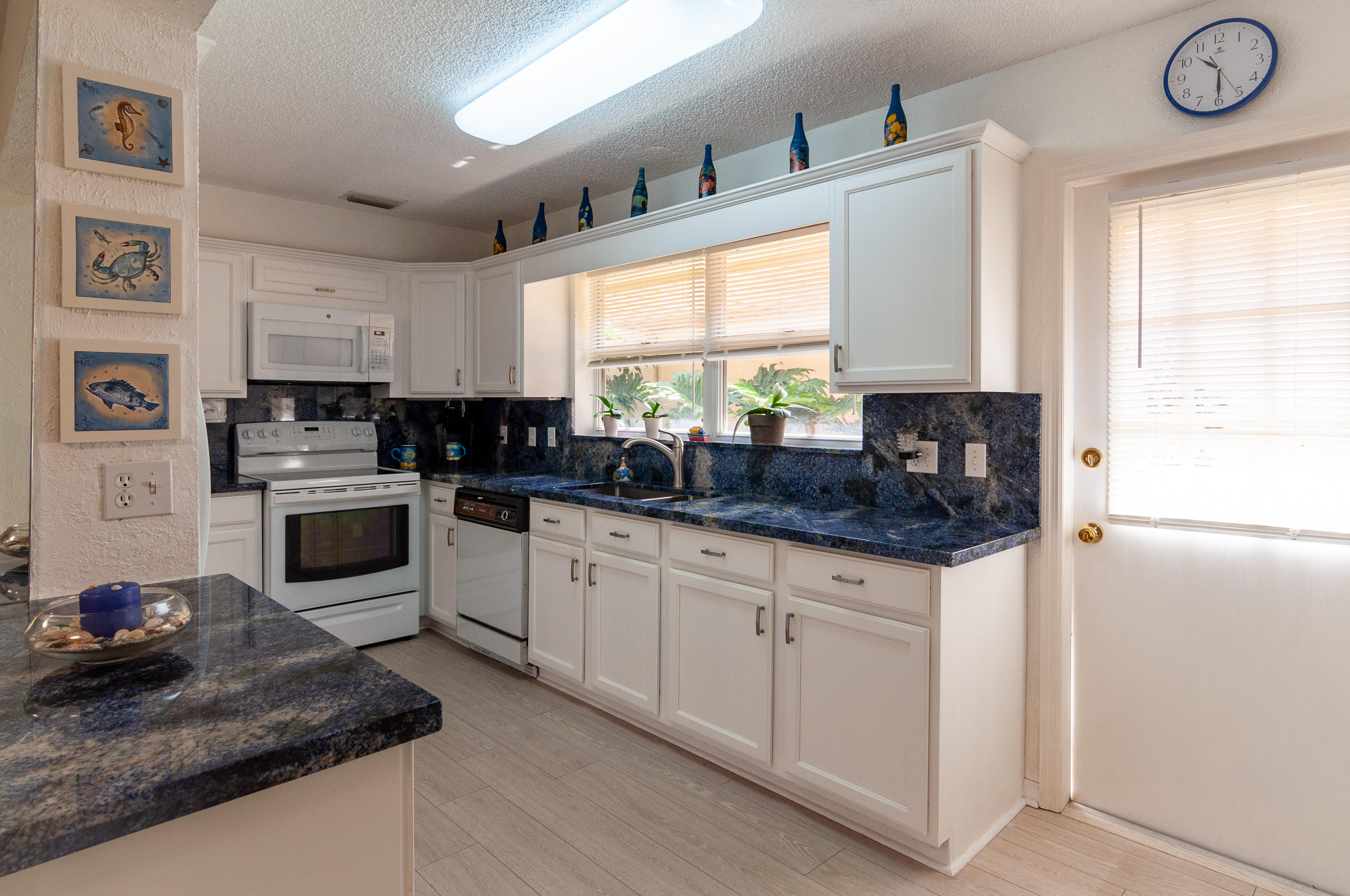 4161 U.S. Highway 1, Unit E2 Jupiter, FL 33477 - Photo 12 of 37 a kitchen with granite countertop a stove a sink a refrigerator and white cabinets