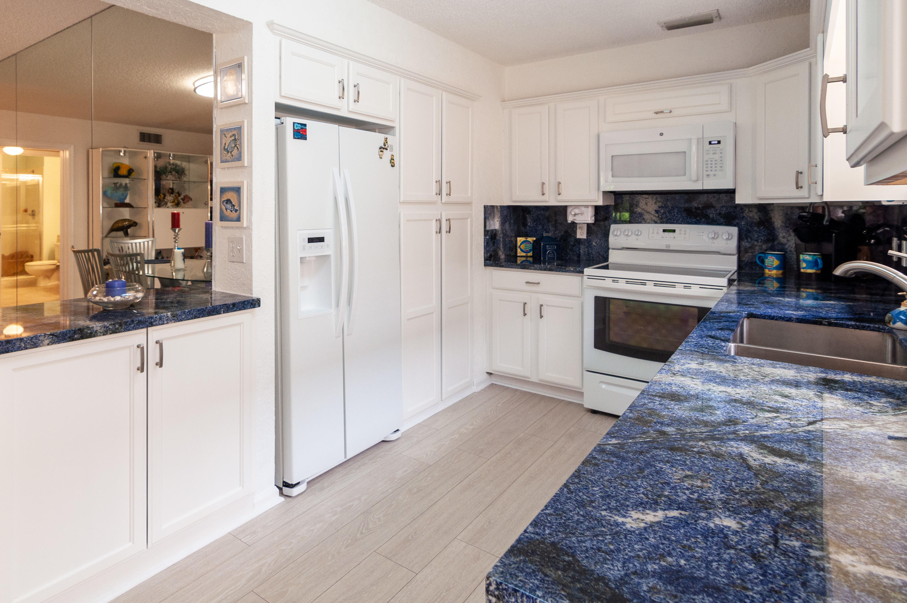 4161 U.S. Highway 1, Unit E2 Jupiter, FL 33477 - Photo 13 of 37 a kitchen with stainless steel appliances granite countertop a refrigerator a stove a sink and white cabinets