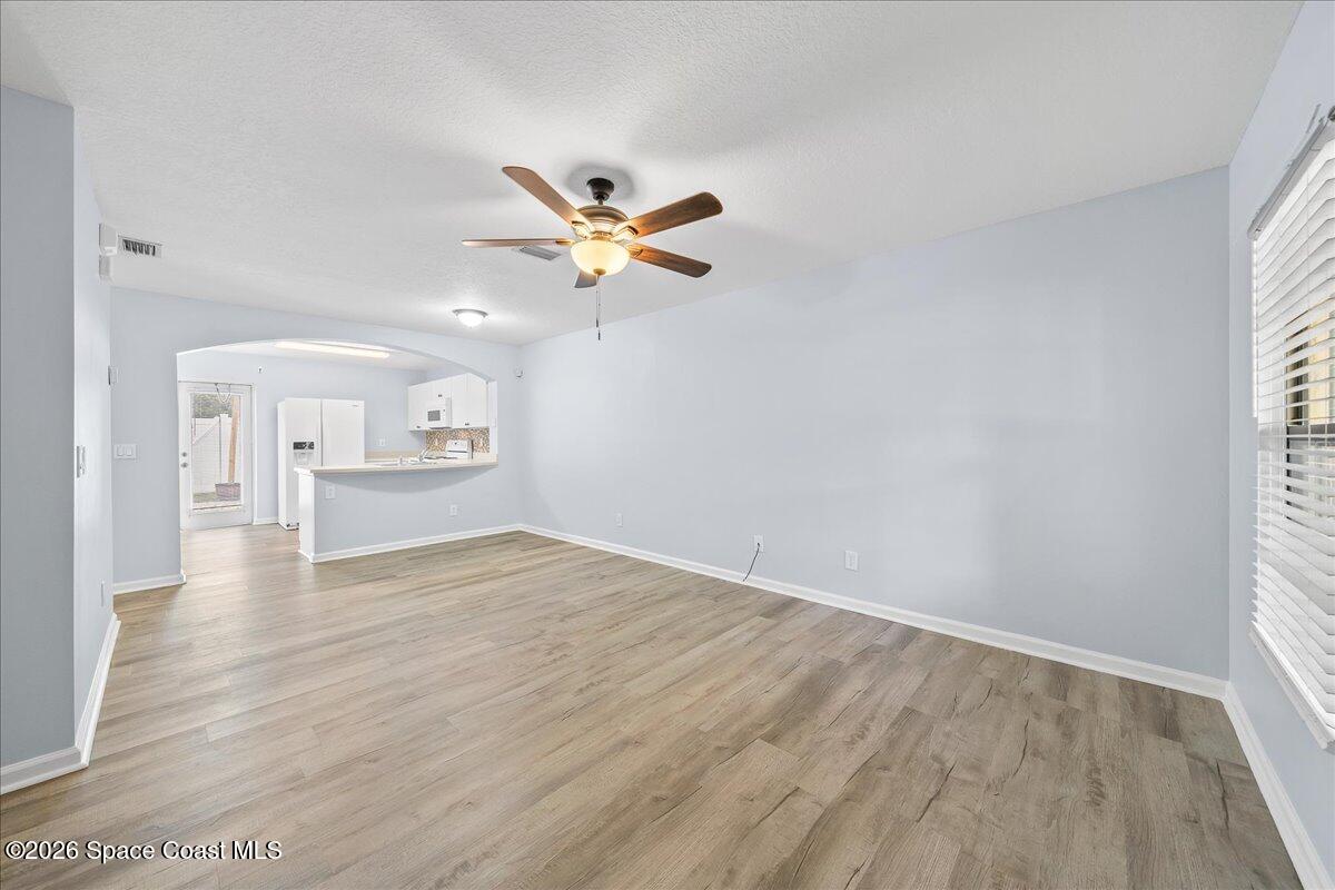 870 Luminary Circle, Unit 103 Melbourne, FL 32901 - Photo 3 of 23 an empty room with wooden floor chandelier fan and windows