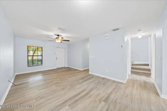 a view of empty room with wooden floor and fan