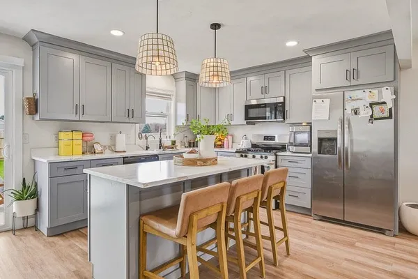 a kitchen with stainless steel appliances granite countertop a refrigerator a sink dishwasher a stove and a dining table with wooden floor