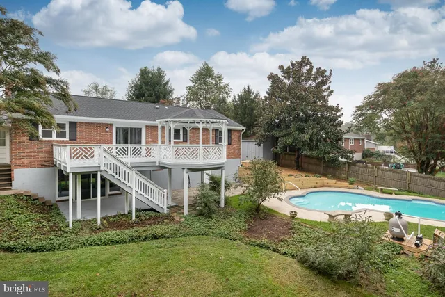 a view of a house with pool and trees in the background