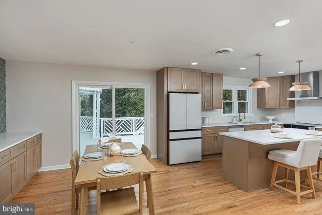 a kitchen with stainless steel appliances granite countertop a stove a refrigerator a sink dishwasher a dining table and chairs with wooden floor