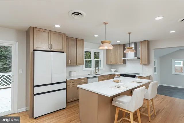 a kitchen with granite countertop a refrigerator a sink a stove a dining table and chairs