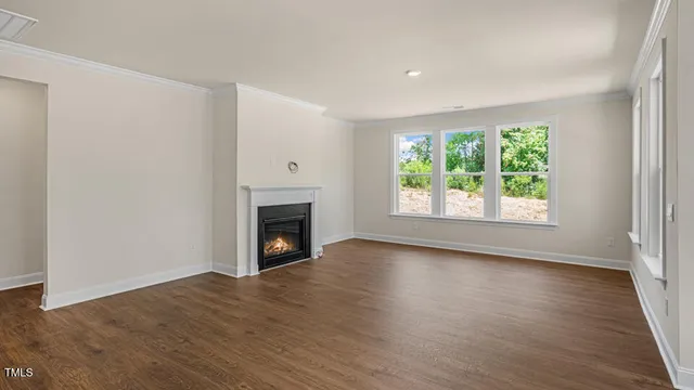 an empty room with wooden floor a fireplace and windows