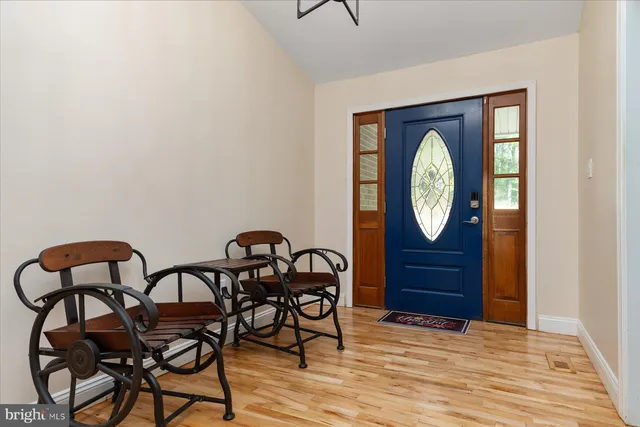 a view of an empty room with wooden floor and a kitchen