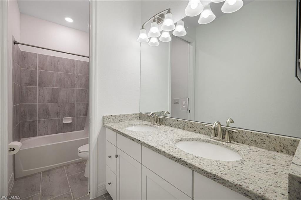 19477 The Pl Boulevard Estero, FL 33928 - Photo 16 of 36 a bathroom with a granite countertop sink a toilet and shower