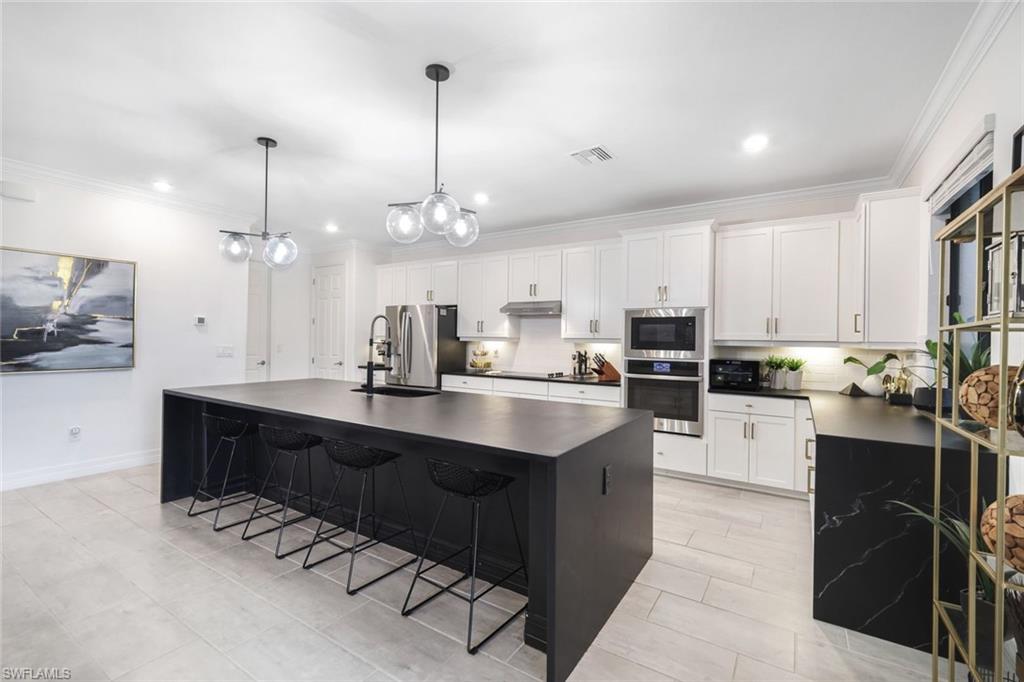 19477 The Pl Boulevard Estero, FL 33928 - Photo 3 of 36 a large kitchen with kitchen island a sink stainless steel appliances and cabinets