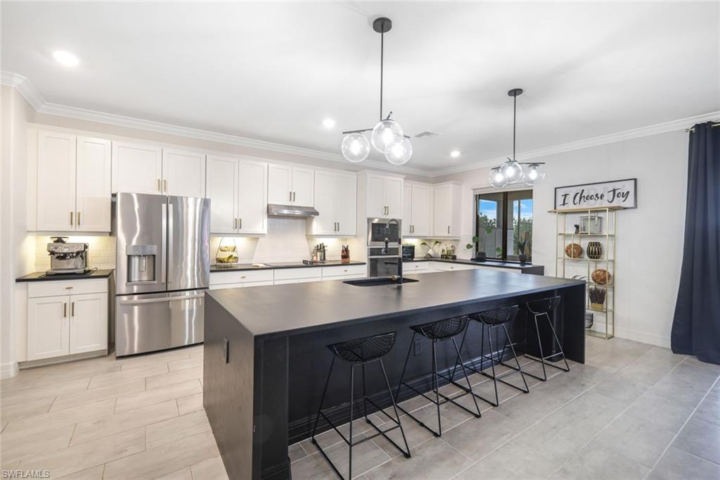 19477 The Pl Boulevard Estero, FL 33928 - Photo 4 of 36 a kitchen with stainless steel appliances granite countertop a sink a stove a refrigerator and island