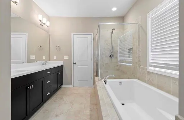 a spacious bathroom with a tub sink shower and mirror