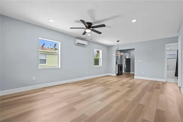 a view of an empty room with window and a kitchen
