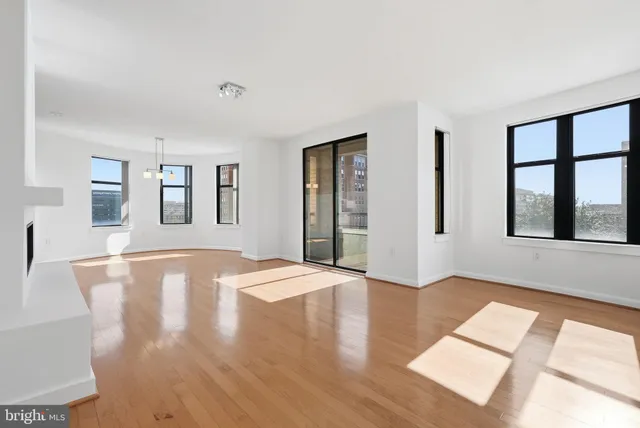 a view of an empty room with window and wooden floor