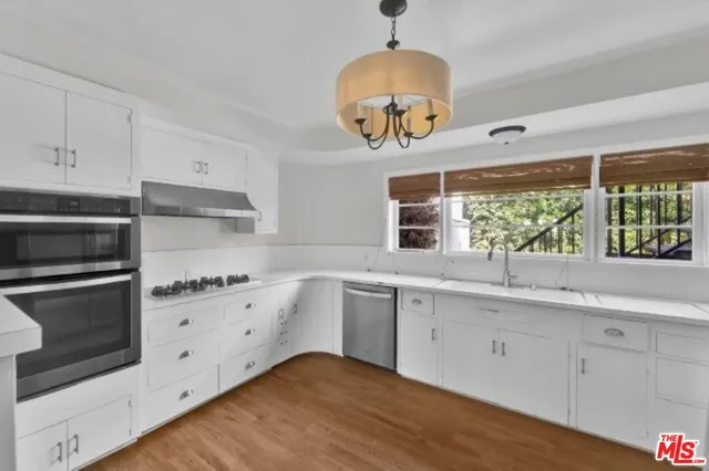 a kitchen with appliances cabinets and a wooden floor