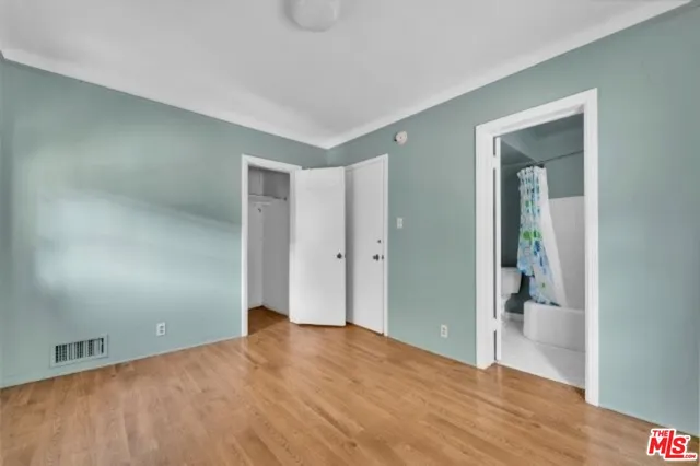 a view of an empty room with closet and wooden floor