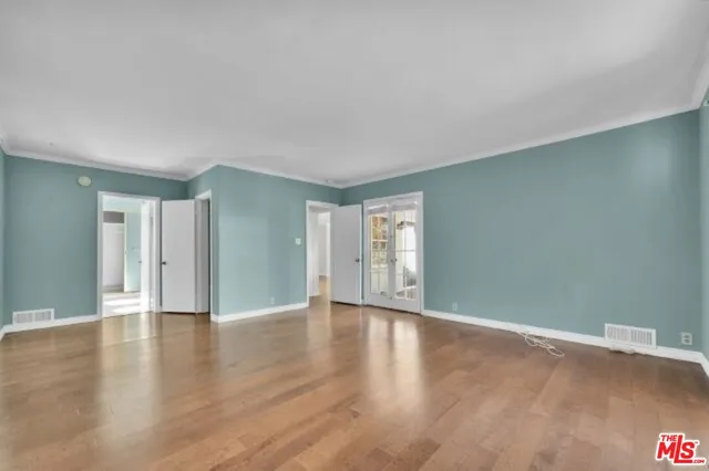 a view of an empty room with window and wooden floor