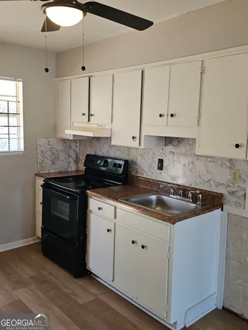 a kitchen with granite countertop white cabinets and black appliances