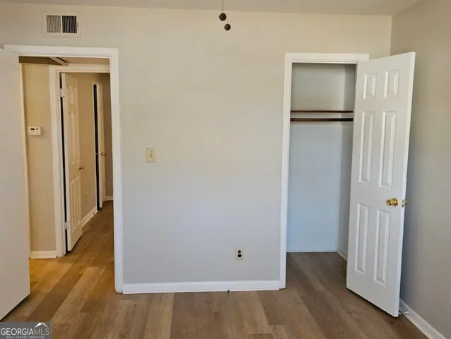 a view of an empty room with wooden floor and closet