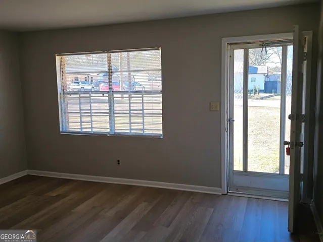 a view of an empty room with wooden floor and a window