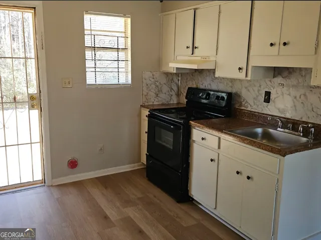 a kitchen with granite countertop a sink stove and cabinets