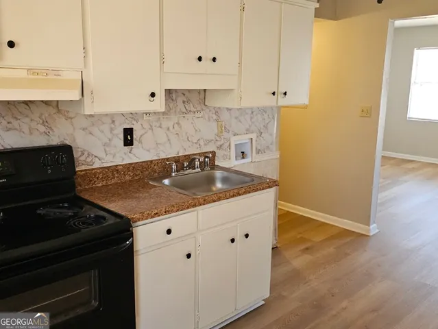a kitchen with granite countertop white cabinets and black appliances