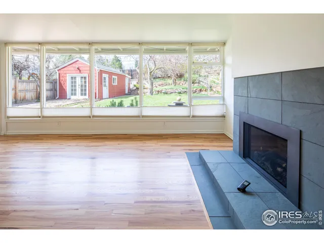a view of an empty room with wooden floor and a fireplace