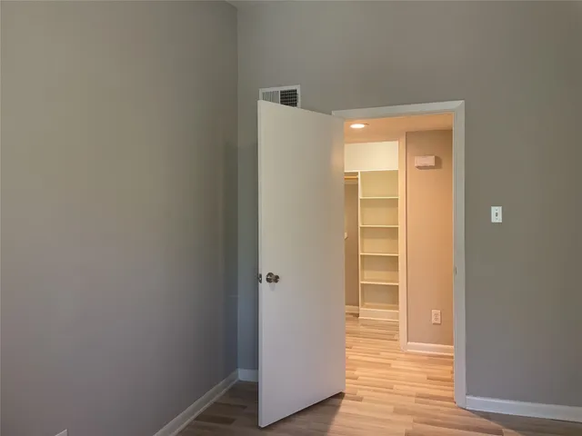 a view of an empty room with wooden floor and closet