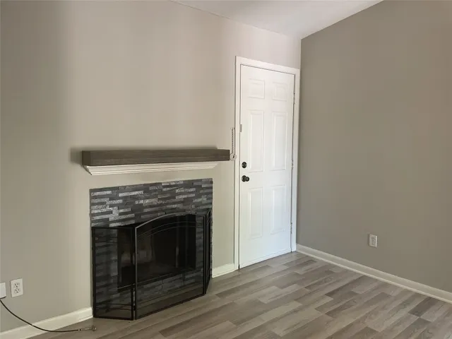a view of empty room with wooden floor and fireplace