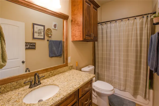 a bathroom with a granite countertop toilet sink and mirror