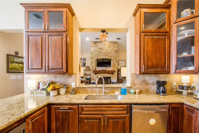 a kitchen with granite countertop stainless steel appliances a sink window and cabinets