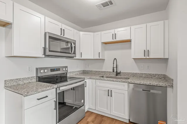 a kitchen with granite countertop white cabinets and white appliances