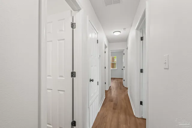 a view of a hallway with wooden floor and a bathroom