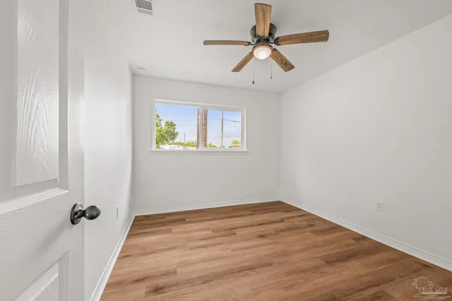 an empty room with a window and a ceiling fan