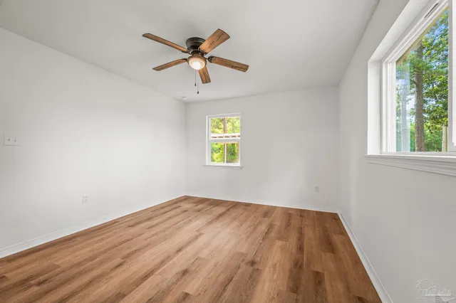 a view of empty room with wooden floor and fan