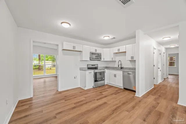 a kitchen with white cabinets and wooden floor