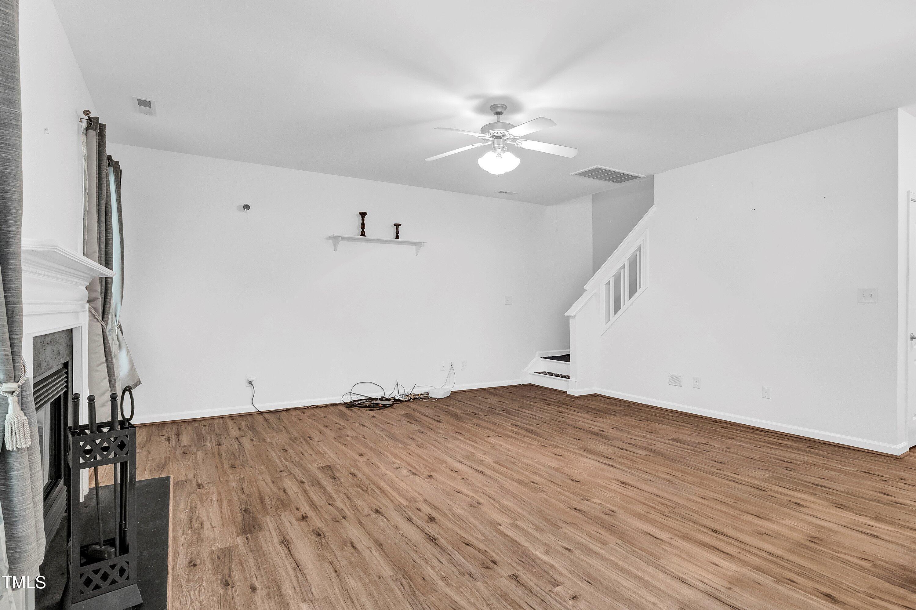 3932 Cane Garden Drive Raleigh, NC 27610 - Photo 14 of 34 a view of an empty room with wooden floor and a ceiling fan