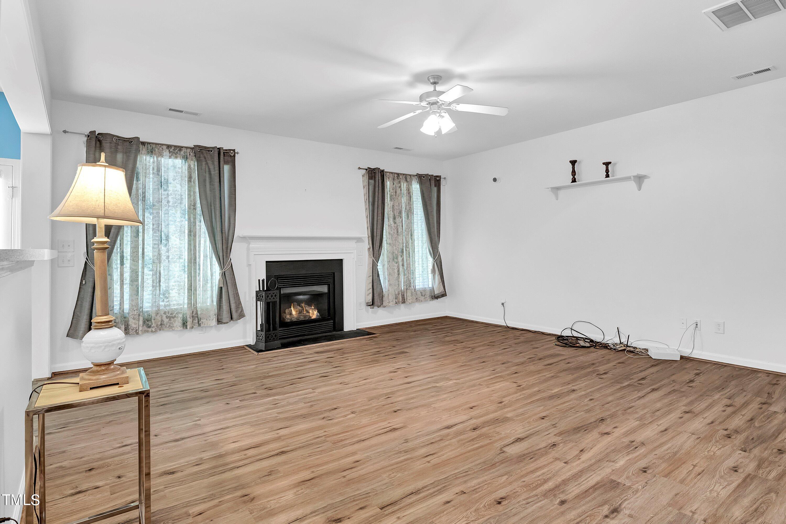 3932 Cane Garden Drive Raleigh, NC 27610 - Photo 15 of 34 a view of an empty room with wooden floor fireplace and a window