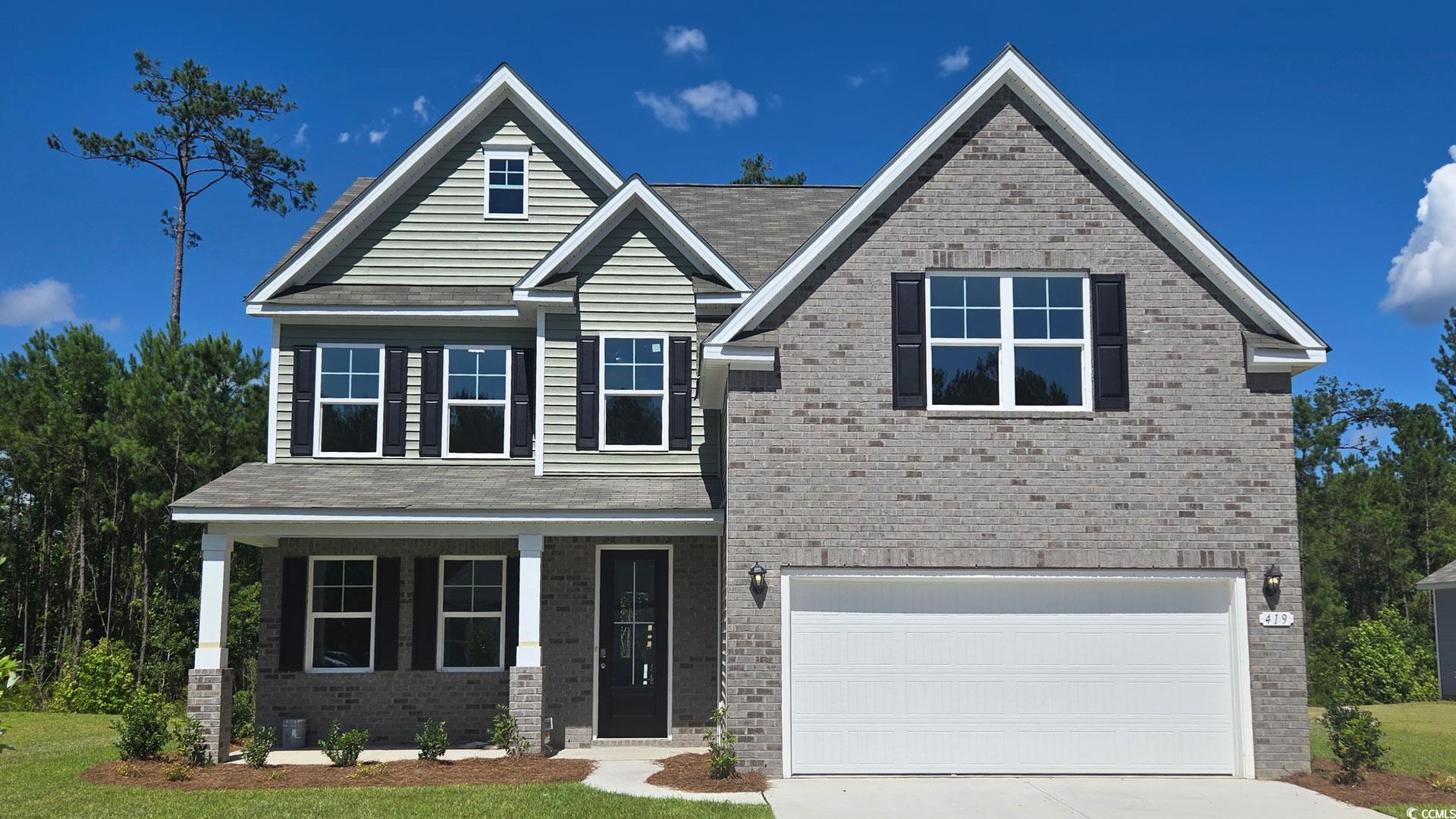 View of front of property featuring brick siding, concrete driveway, a garage, and covered porch