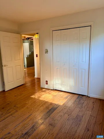 a view of an empty room with wooden floor and closet area