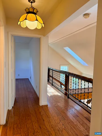 a view of a hallway with wooden floor and chandelier