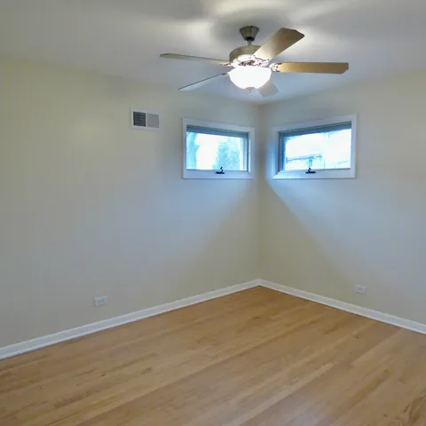 a view of a room with wooden floor and a ceiling fan