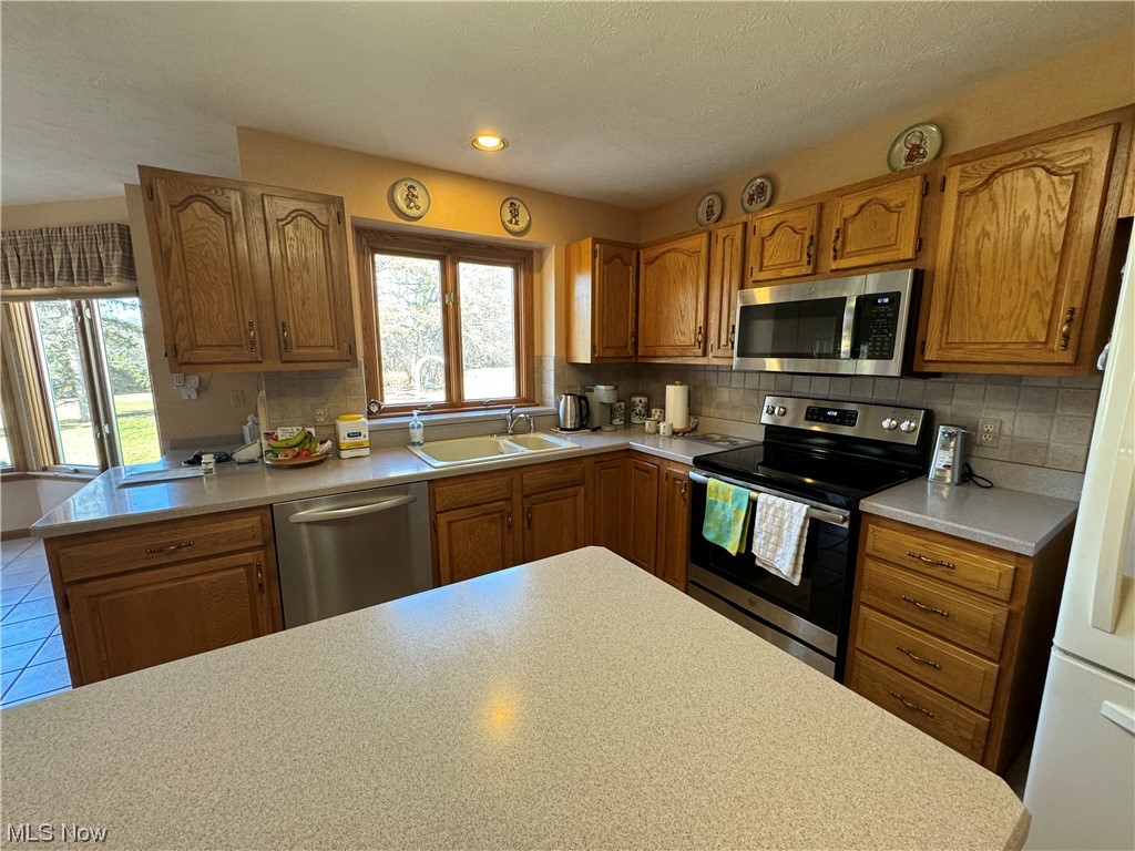 9615 Johnnycake Ridge Road Mentor, OH 44060 - Photo 21 of 35 Kitchen with appliances with stainless steel finishes, a healthy amount of sunlight, backsplash, and sink