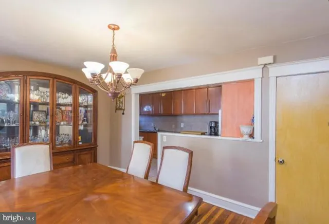 a kitchen with kitchen island a refrigerator a stove a sink dishwasher a dining table and chairs with wooden floor