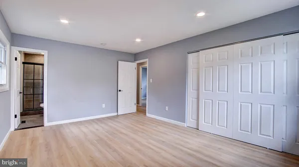 an empty room with wooden floor & closet area