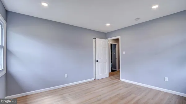a view of an empty room with wooden floor and closet